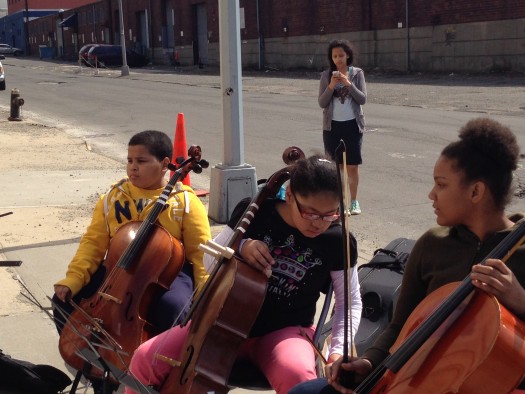 Local children playing cello join the demonstration